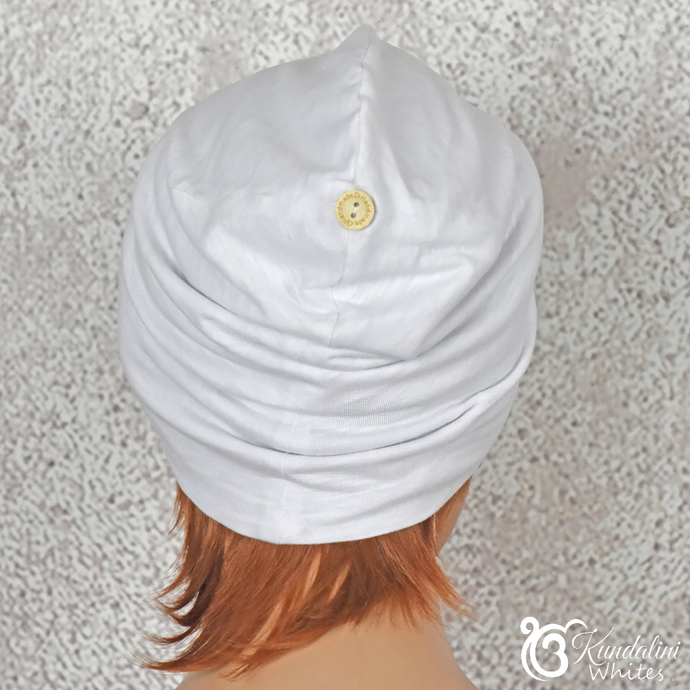 White slouch beanie with a button on a textured gray background