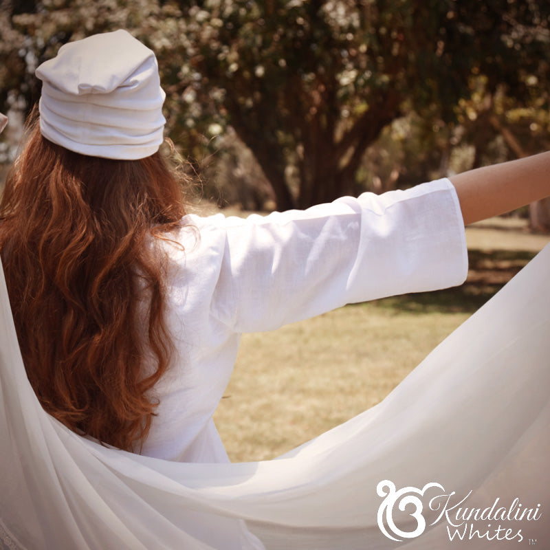 Woman in a white outfit sitting in a hammock with trees in the background