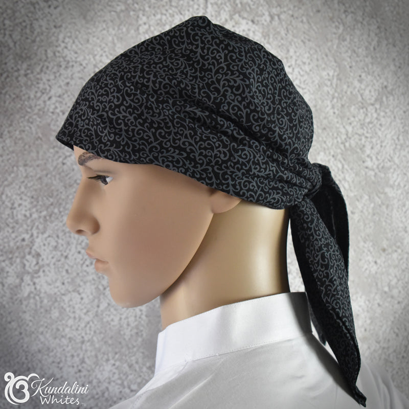 Mannequin head wearing a black patterned headscarf against a gray background
