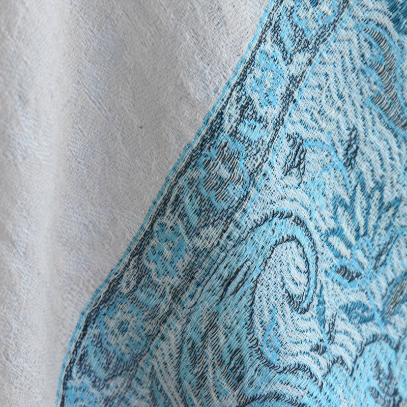 Close-up of a textured fabric with blue and black pattern on a light gray background