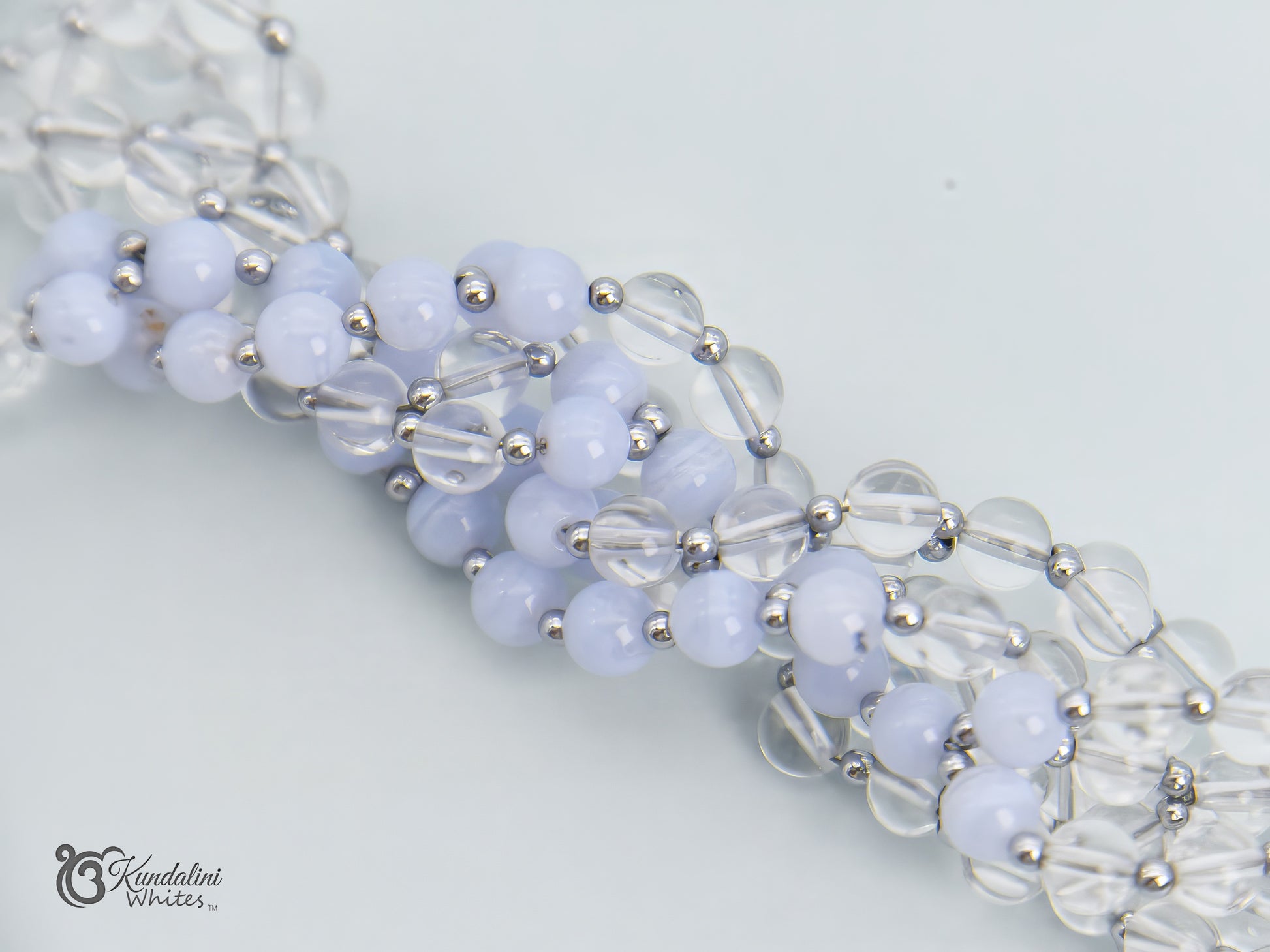 Close-up of a blue lace agate and clear quartz tantric mala on a white background