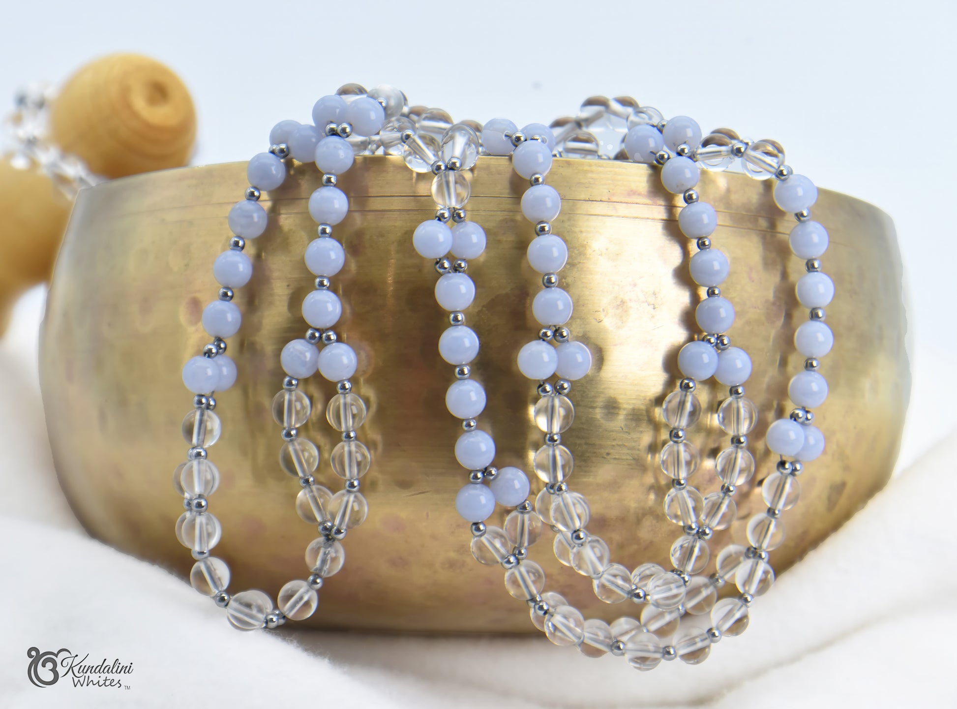 Tantric mala on a brass bowl with a white background