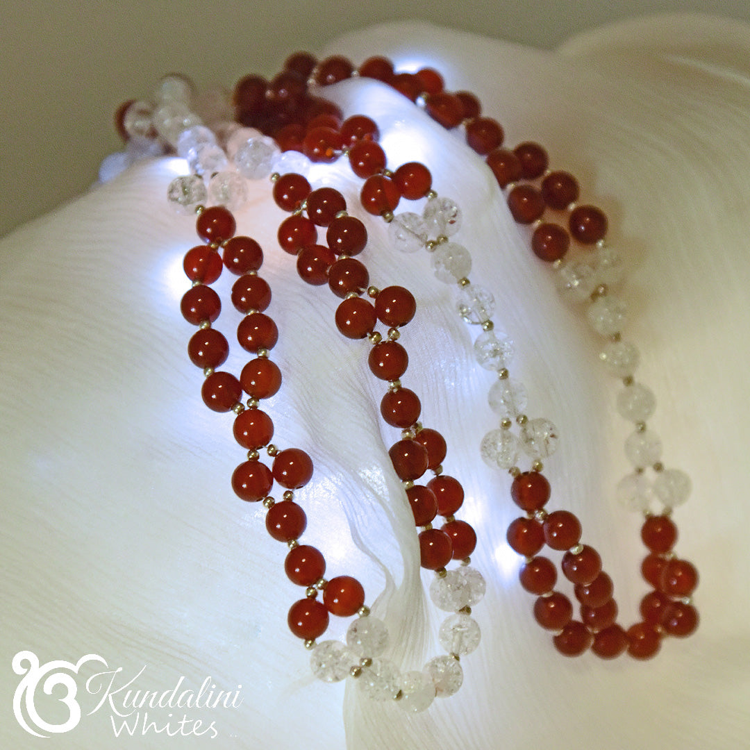 Red and white beaded necklace on white fabric with 'Kundalini Whites' branding.