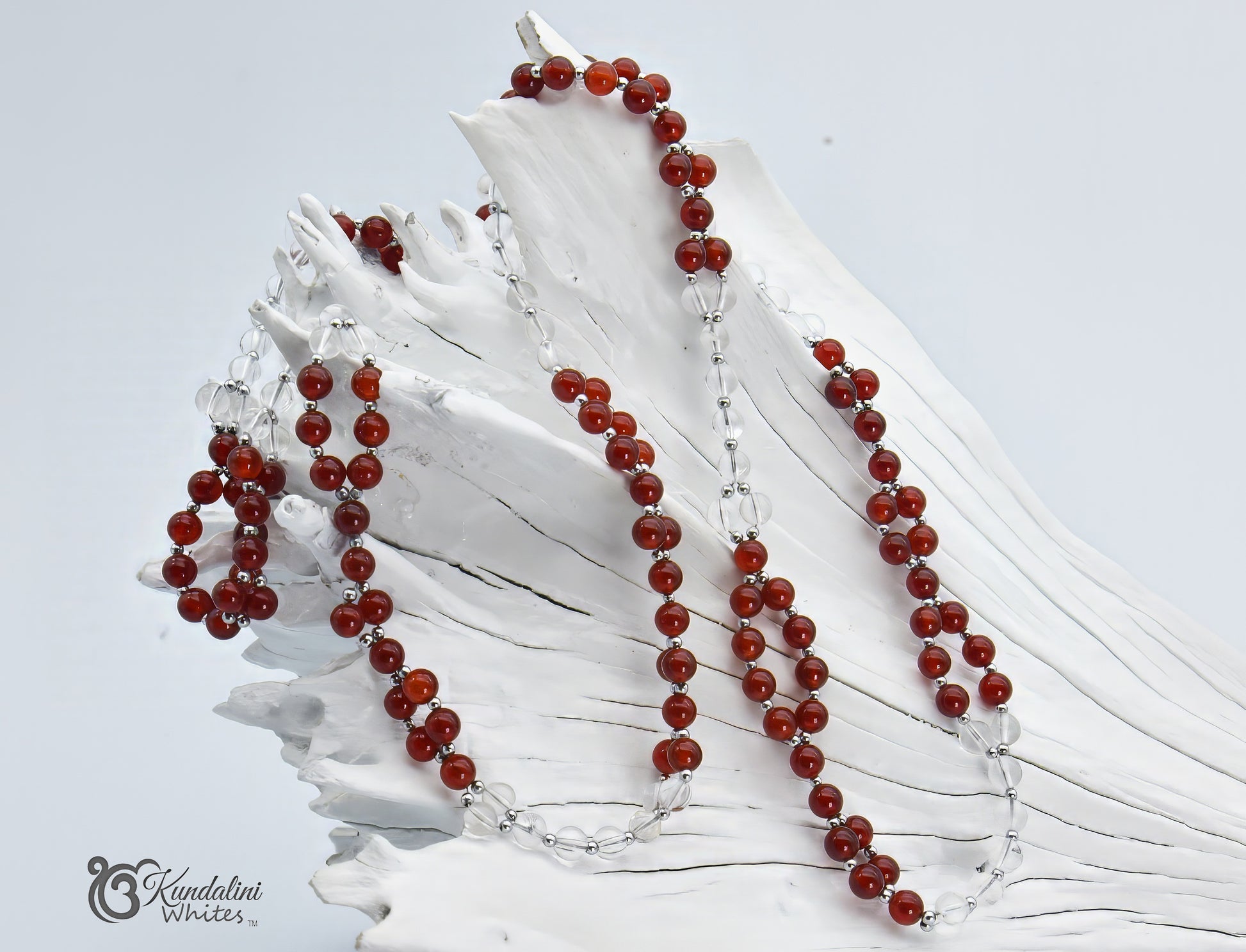 Red and clear beaded tantric necklace on a white shell 