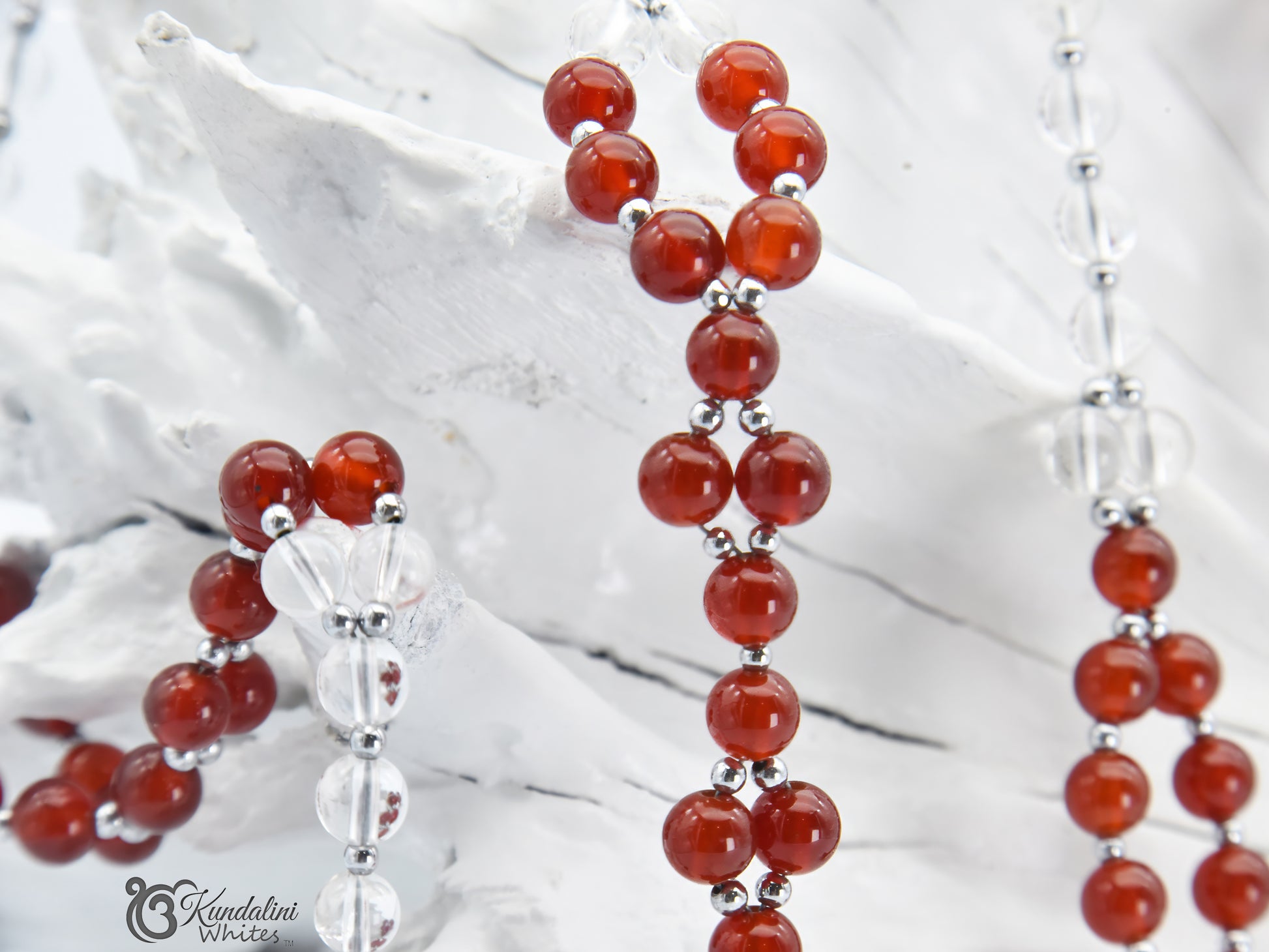 Tantric necklace closeup with red and clear beads on a white textured background