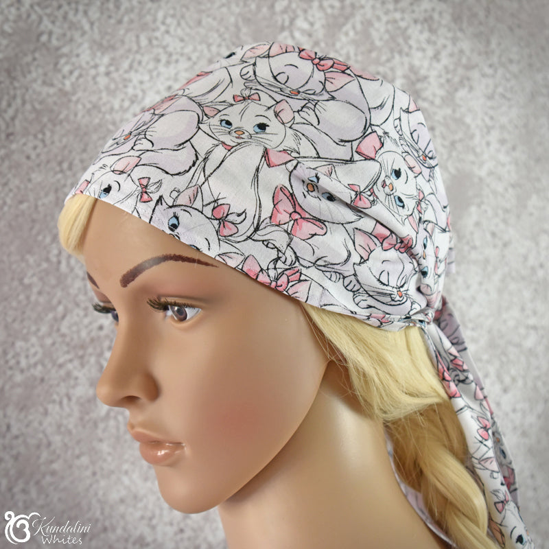 Mannequin head wearing a patterned headscarf with cartoon cats on a neutral background