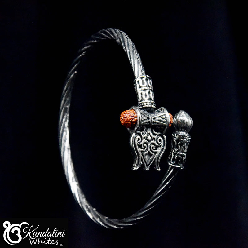 Silver bracelet with intricate design and red stone on a black background