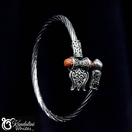 Silver bracelet with intricate design and red stone on a black background