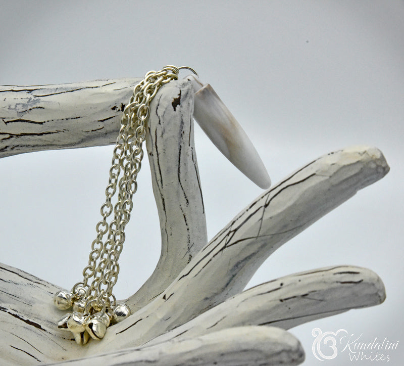 Silver ornament with small pendants on a piece of wood against a white background
