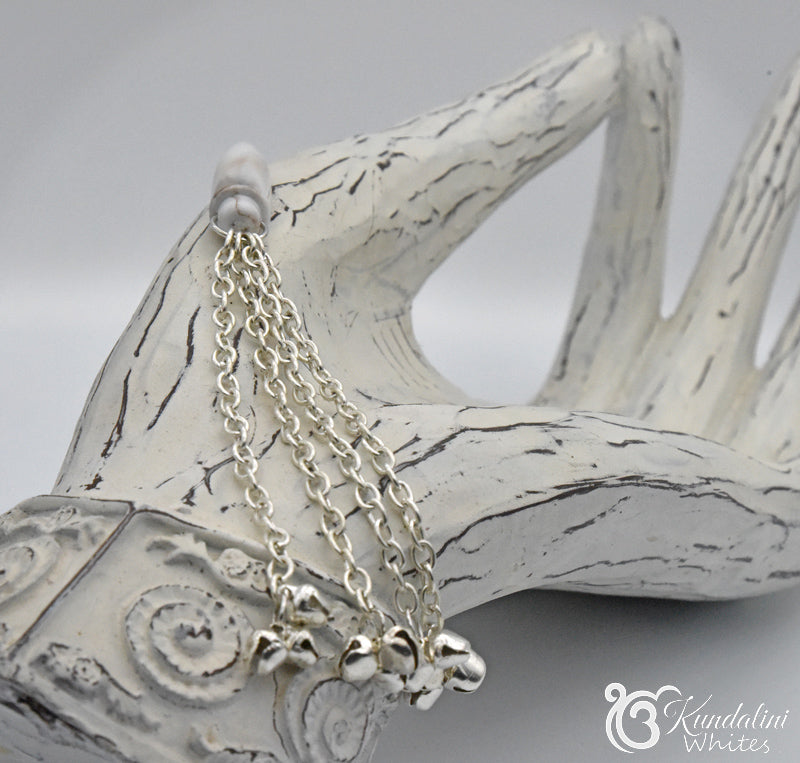 Silver chain ornament on a decorative wooden hand with 'Kundalini Whites' branding.