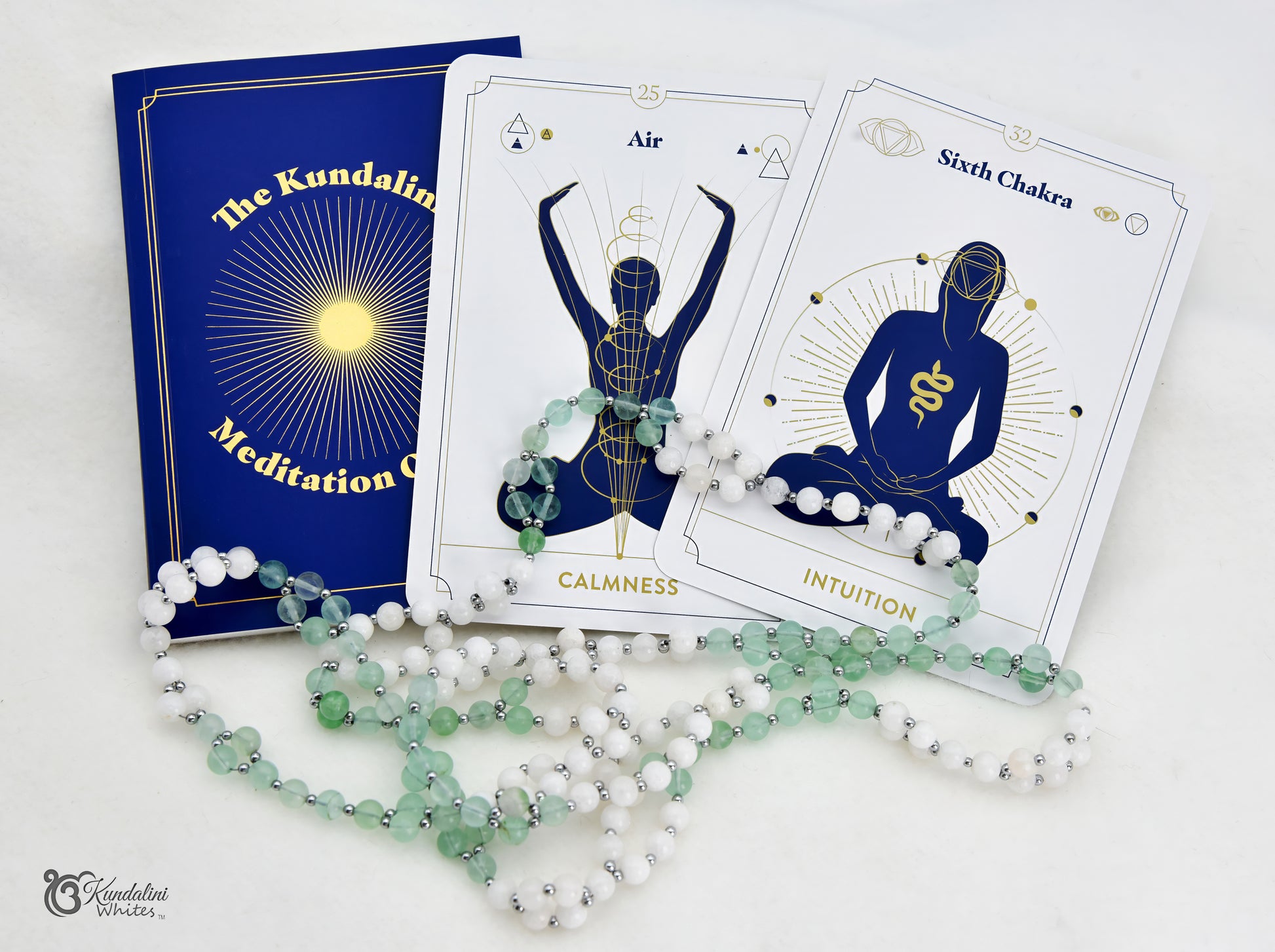 The Kundalini Meditation Oracle book featuring two white and blue tarot-style cards, and a fluorite and white agate Tantric Mala.