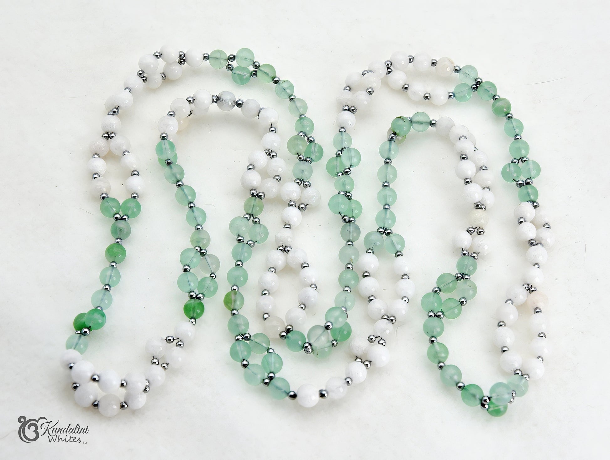 A fluorite and white agate Tantric Mala, arranged in loops on a white background.