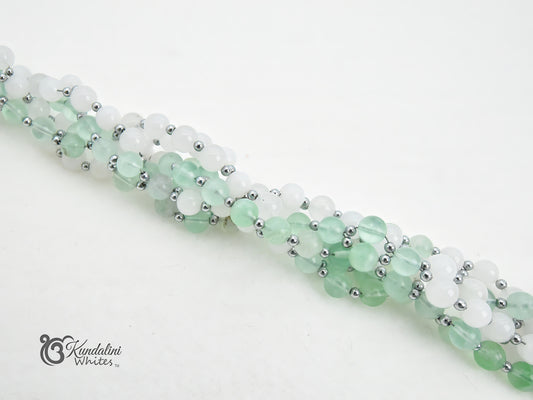 A close-up of a fluorite and white jade Tantric Mala, displayed diagonally on a clean white background.