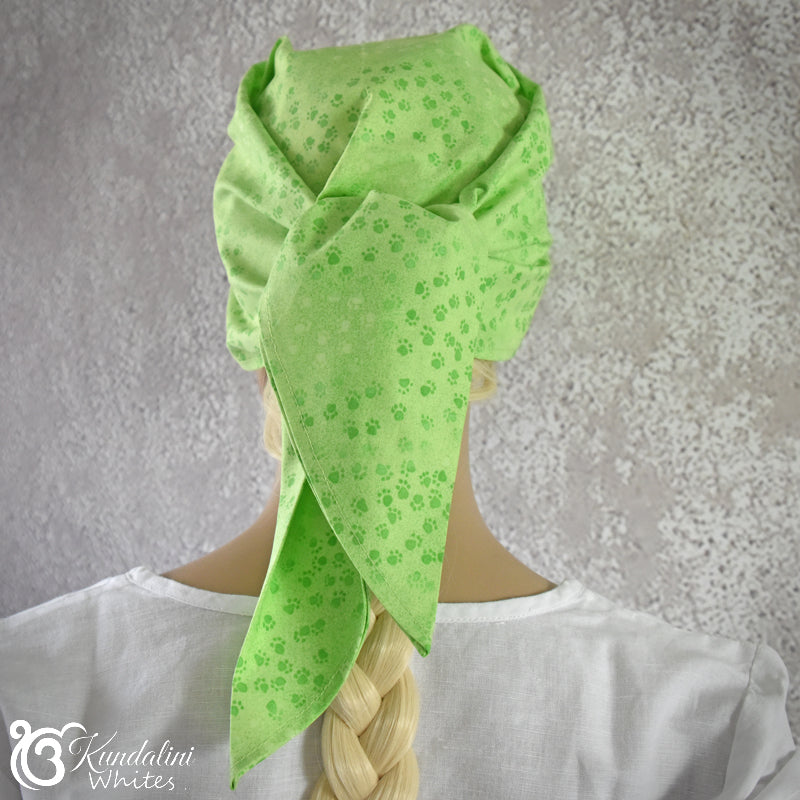 Person wearing a green patterned headscarf on a gray background
