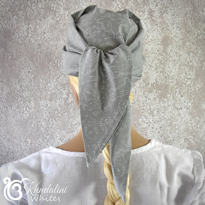 Person wearing a gray patterned headscarf on a textured gray background
