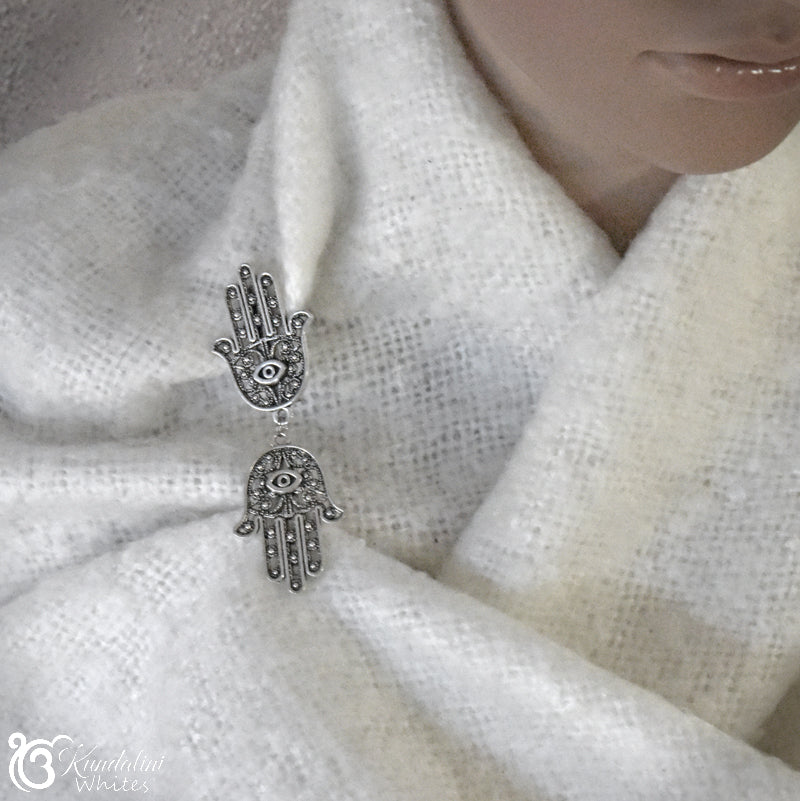 Silver hamsa hand shawl holder on a white shawl.