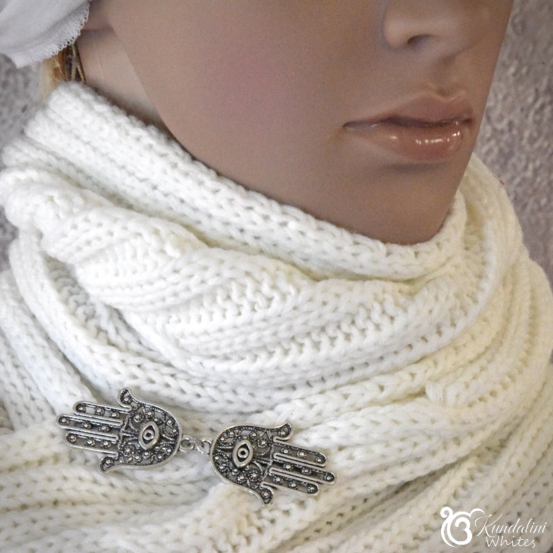 White knitted scarf with Hamsa hand charm held by a mannequin