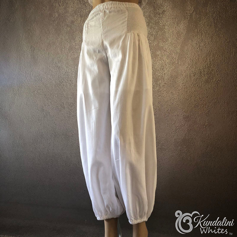 White pants on a mannequin against a textured gray background with 'Kundalini Whites' branding.