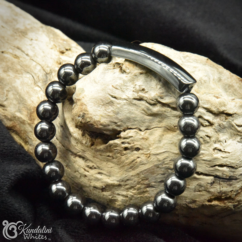 Silvery black beaded bracelet on wood with 'Kundalini Whites' branding.