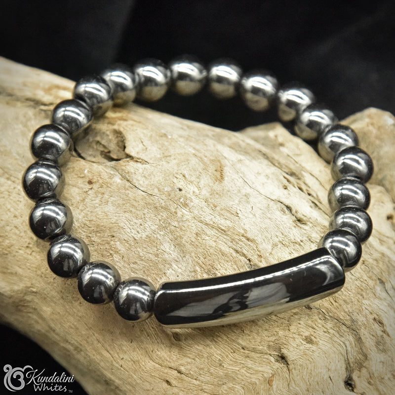 Silvery black beaded bracelet with a black bar clasp on a wooden surface
