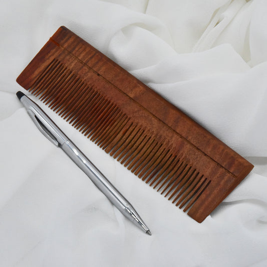 Wooden comb and pen on a white fabric background