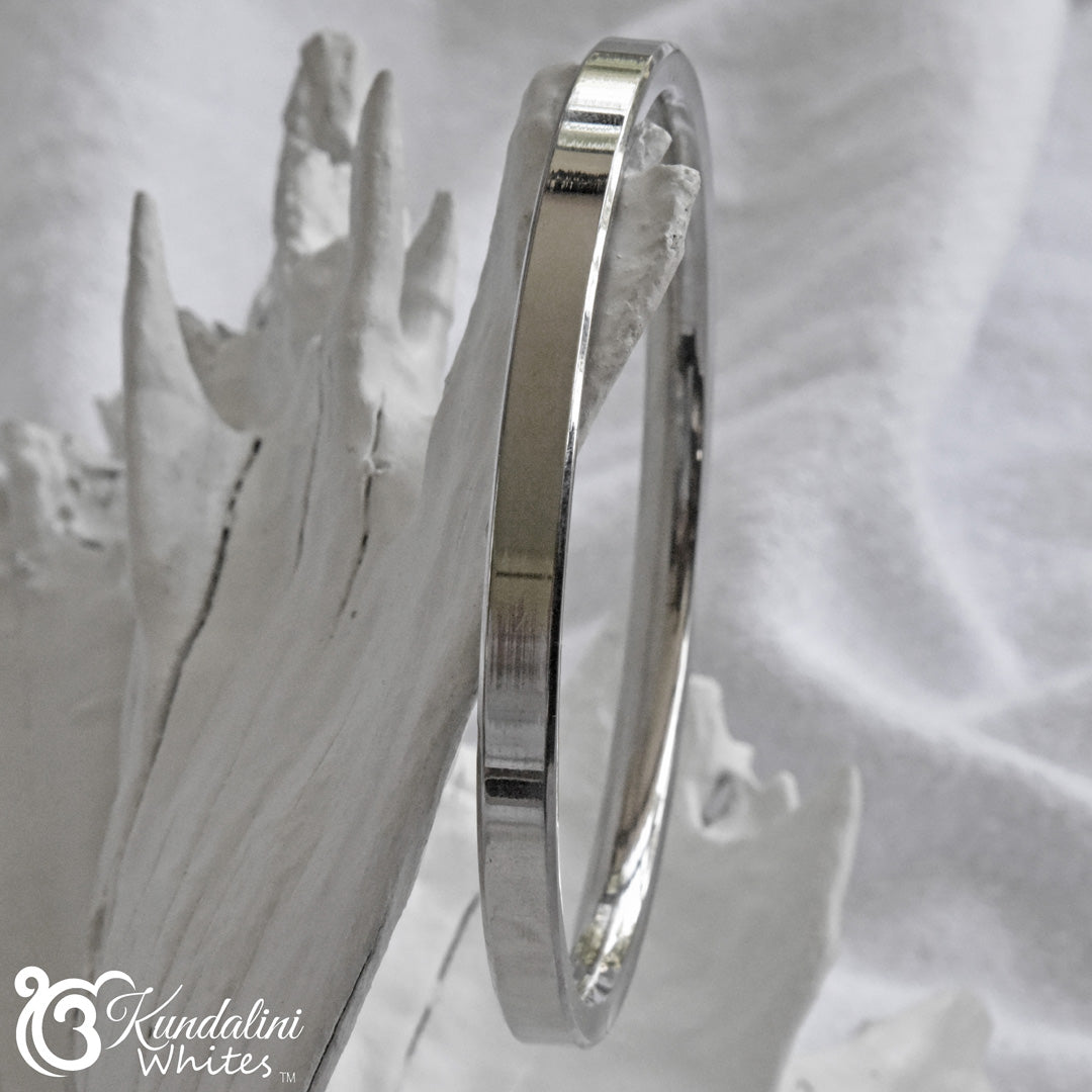 Steel Kara bracelet on a textured white background with 'Kundalini Whites' branding.