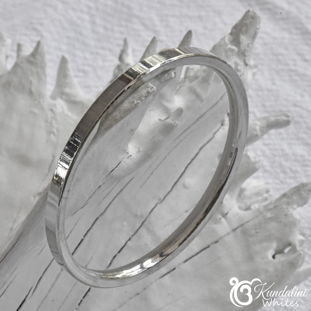 Steel bracelet on a textured white surface with 'Kundalini' branding.