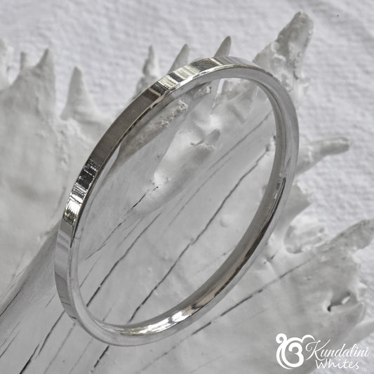 Steel bracelet on a textured white surface with 'Kundalini' branding.