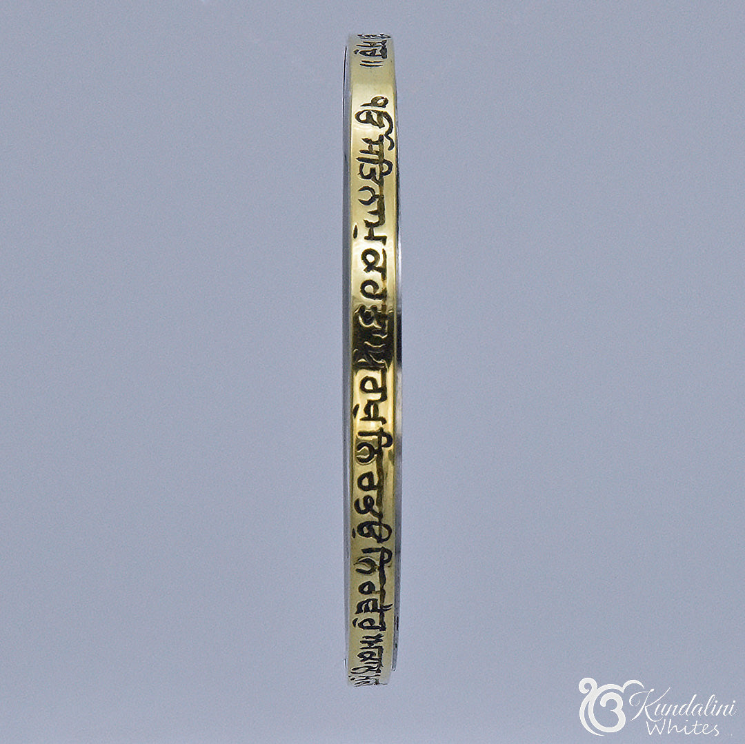 Steel and brass Kara sideview with engraved text on a gray background