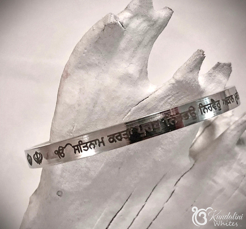 Steel bracelet with engraved text on a painted wood background