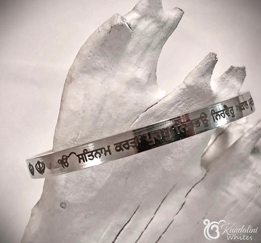 Steel bracelet with engraved text on a painted wood background