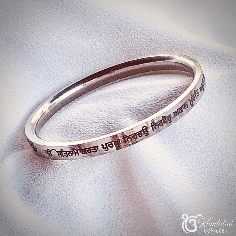 Steel bracelet with engraved text on a white fabric background