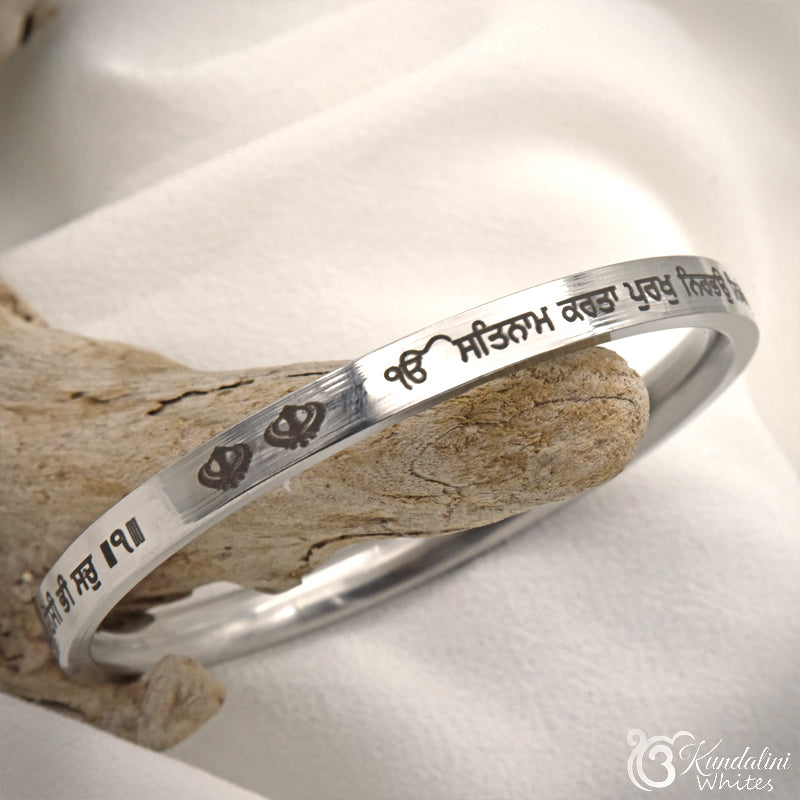 Steel bracelet with engraved text on a wooden surface