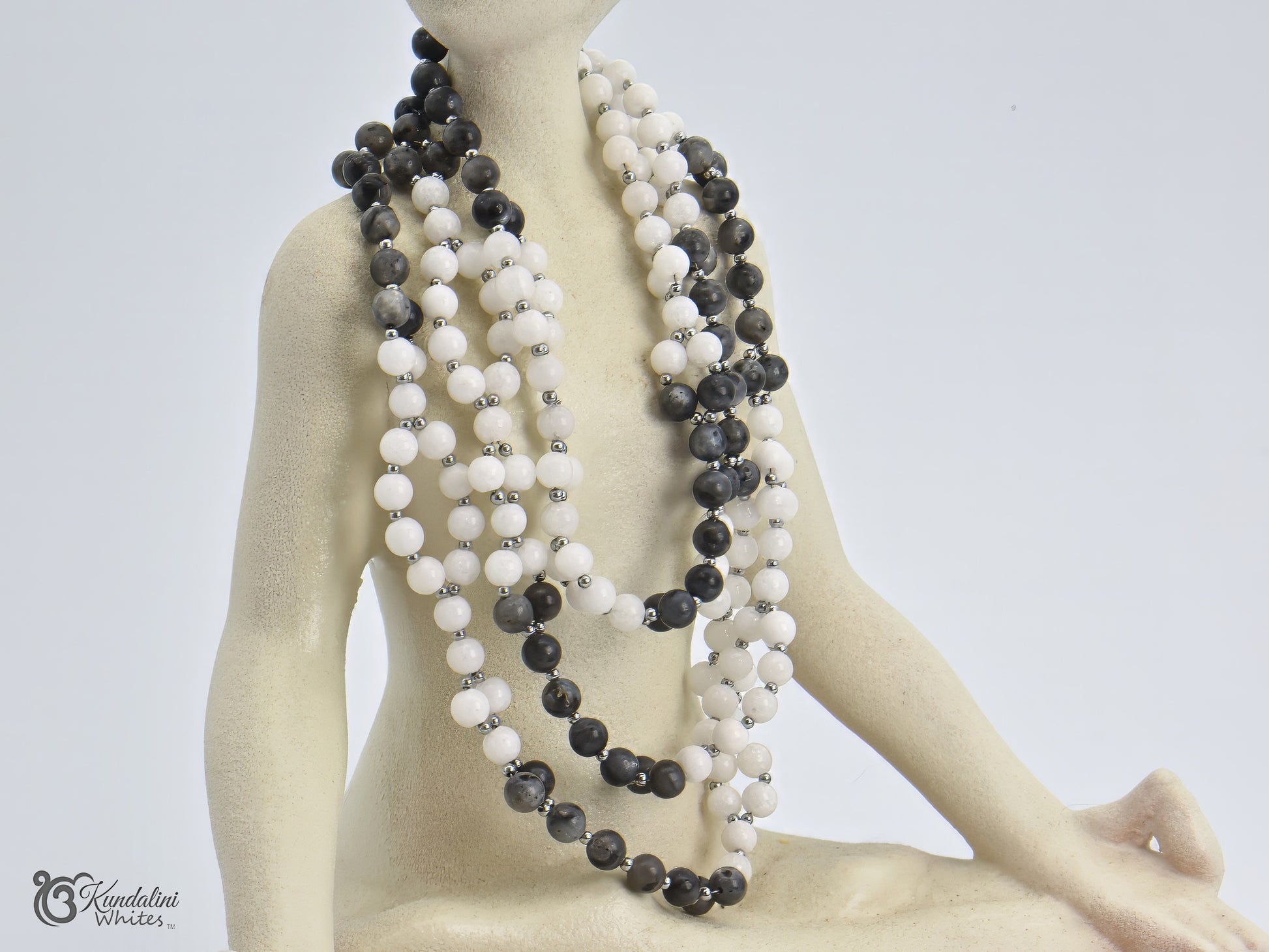 Mannequin wearing a tantric necklace with black and white beads on a plain background
