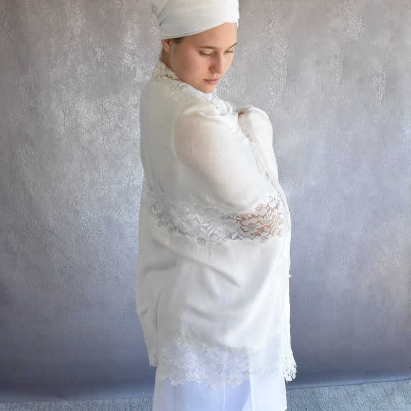 Woman wearing a white lace shawl against a plain background