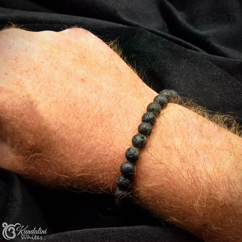 Black beaded bracelet on a wrist with a black fabric background