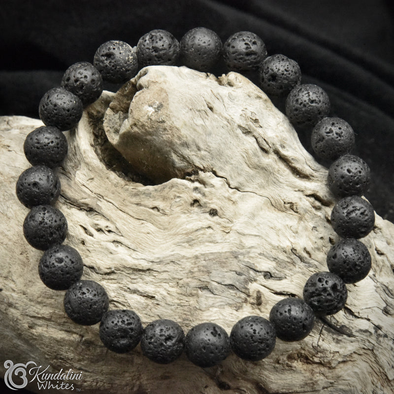 Lava stone bracelet on a piece of driftwood with 'Kundalini Whites' branding.