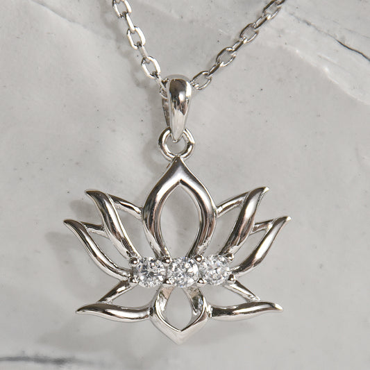 Silver lotus flower pendant with diamonds on a chain against a marble background