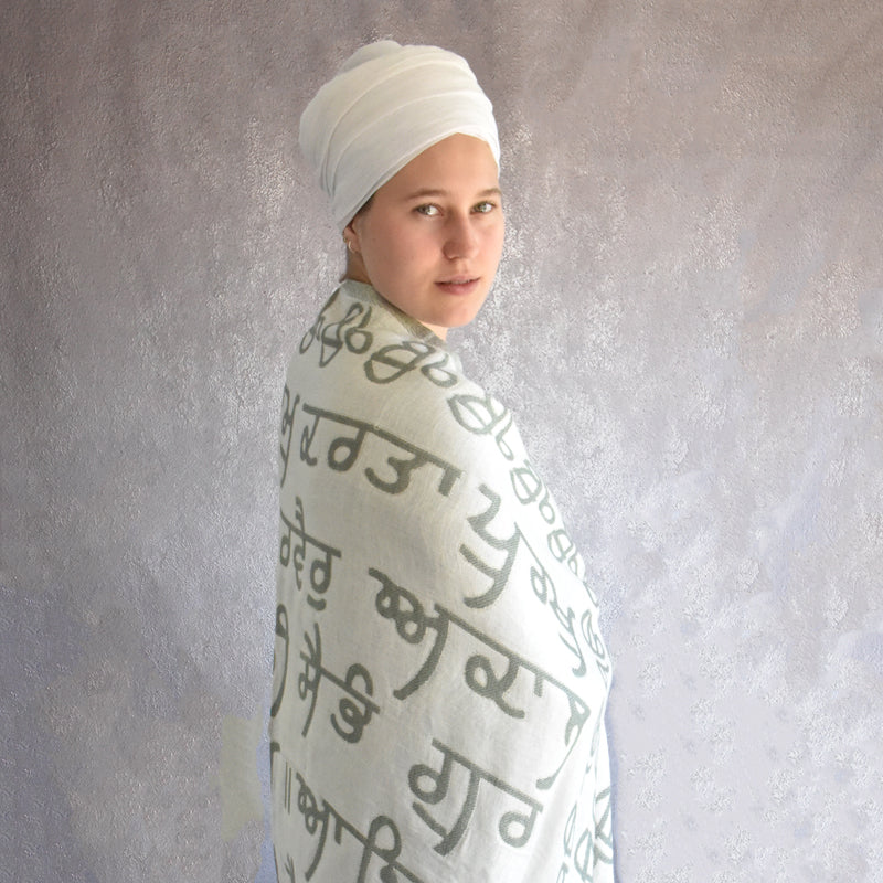 Person wearing a white garment with text, standing against a textured gray background