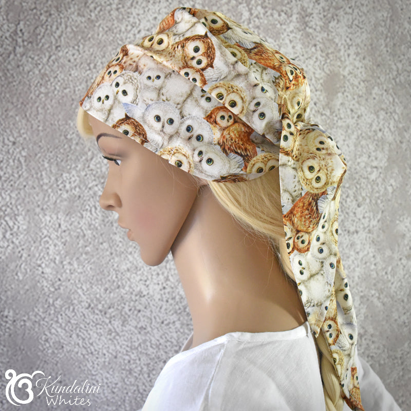 Mannequin head wearing a patterned headscarf with owls on a neutral background