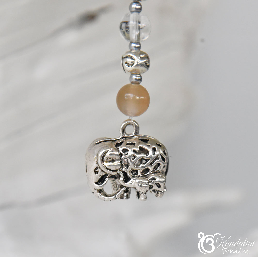 Silver elephant charm with beads on a blurred background