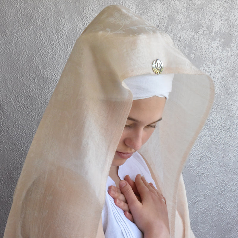 Woman wearing a white stole and veil against a gray textured wall