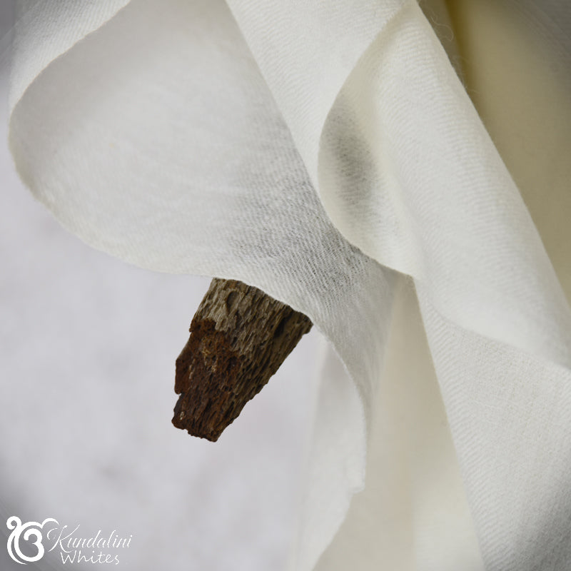 Close-up of white fabric with a piece of wood on a neutral background