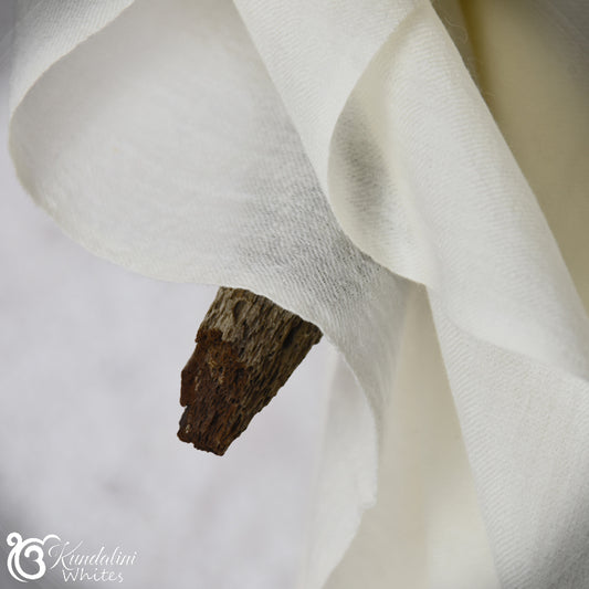 Close-up of white fabric with a piece of wood on a neutral background