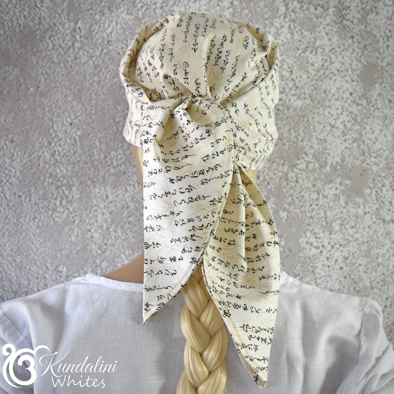 Person wearing a patterned headscarf with braided hair against a gray background