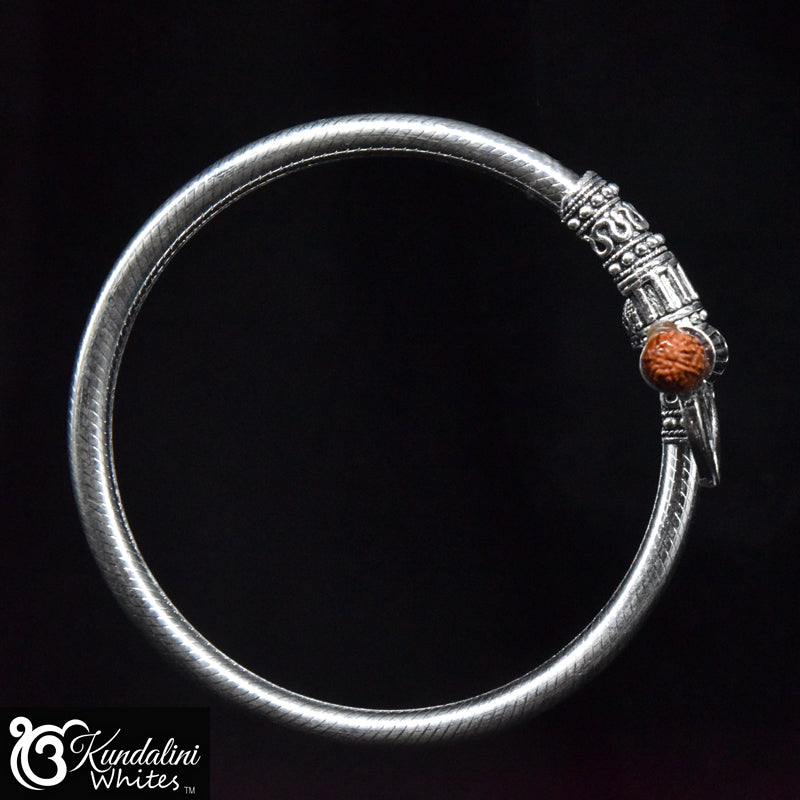 Silver bracelet with a decorative design on a black background