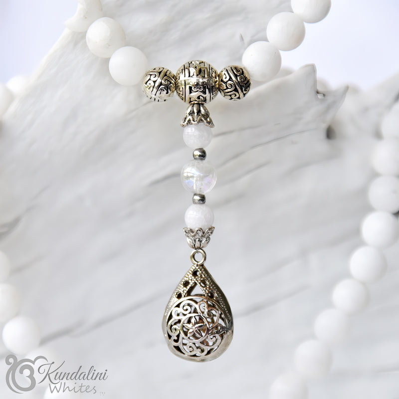 White beaded necklace with a silver filigree pendant on a white background