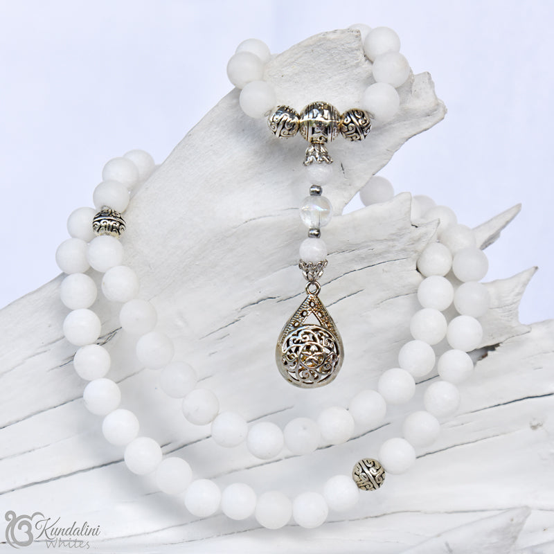 White beaded necklace with silver teardrop pendant on a white background