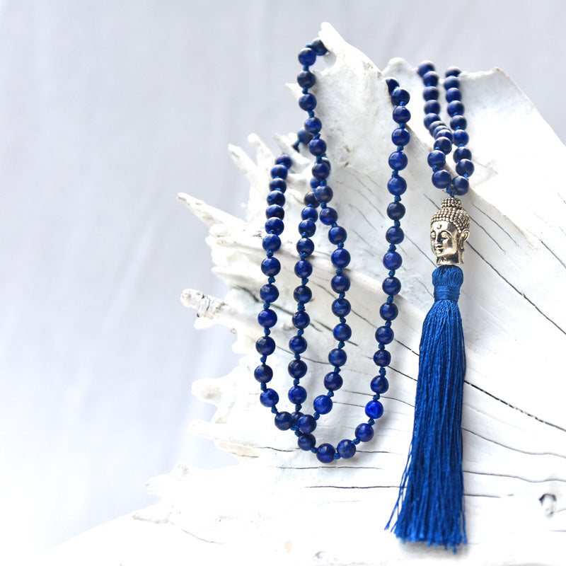 Blue beaded necklace with tassel on a white surface