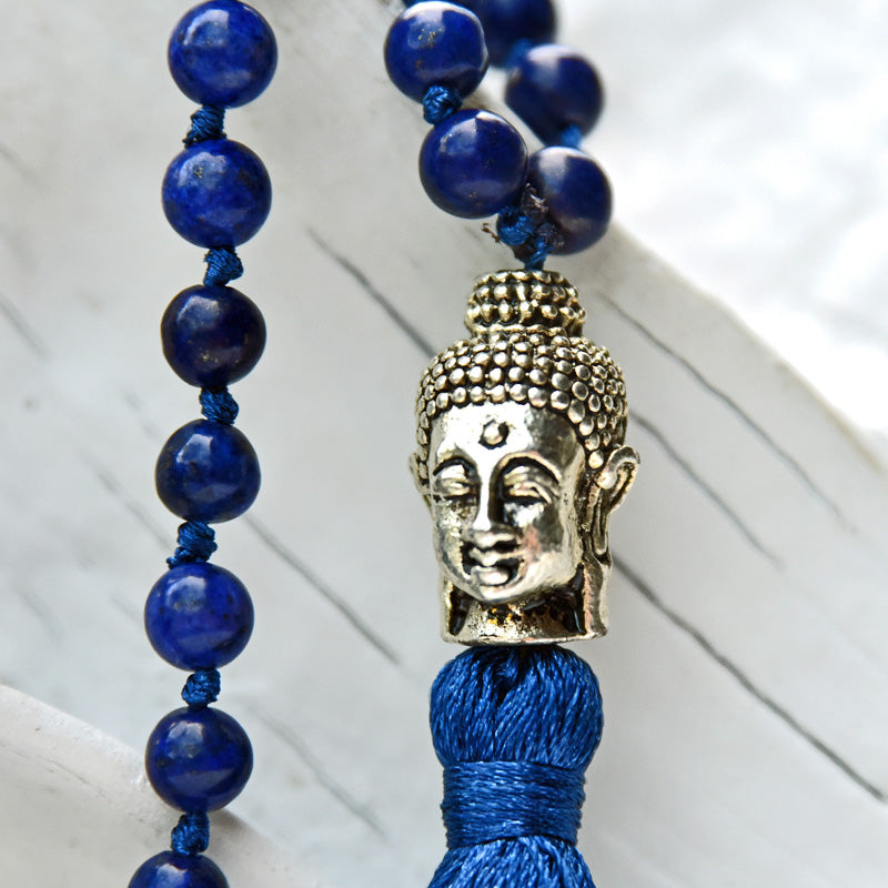 Necklace with blue beads and Buddha head charm on a white background